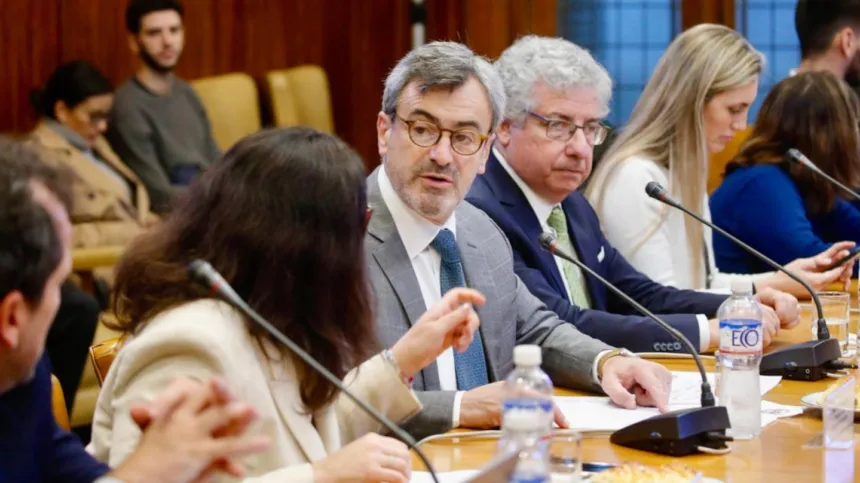 Representantes participan de una reunión alrededor de una mesa con micrófonos.