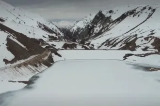 Camino de montaña cubierto de nieve y hielo entre cumbres.