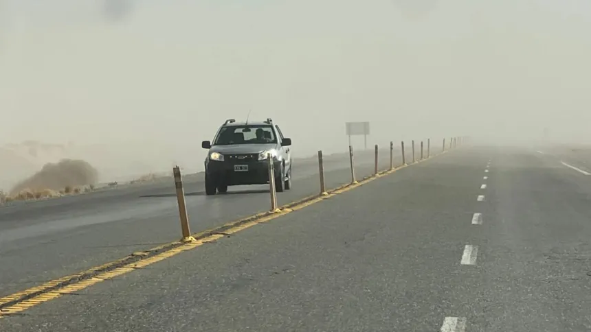 Un vehículo avanza por una ruta con polvo y poca visibilidad.