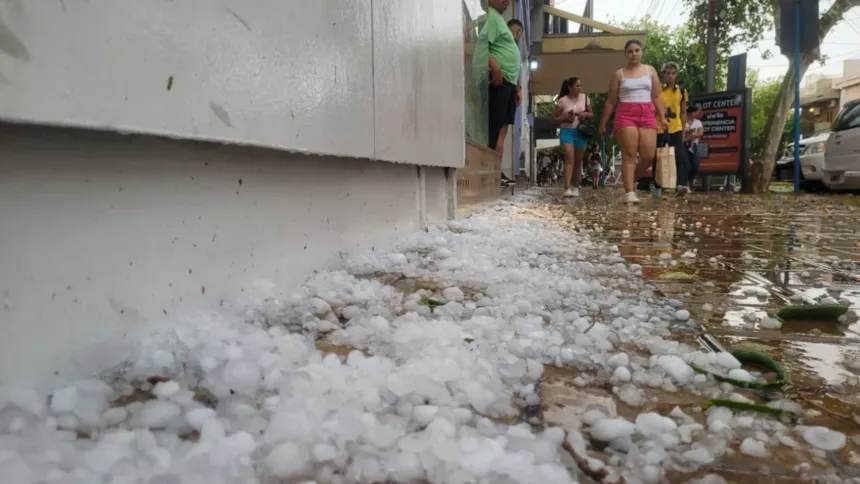 Granizo acumulado sobre una calle mojada mientras varias personas caminan.