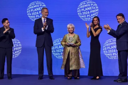 Isabel Allende sostiene el premio en un escenario junto a asistentes que aplauden.