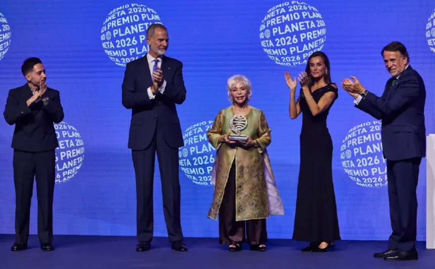 Isabel Allende sostiene el premio en un escenario junto a asistentes que aplauden.