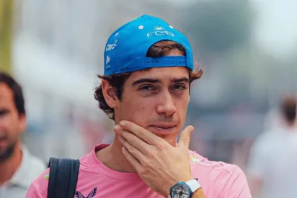 Franco Colapinto con gorra azul y camiseta rosa en un entorno de automovilismo.