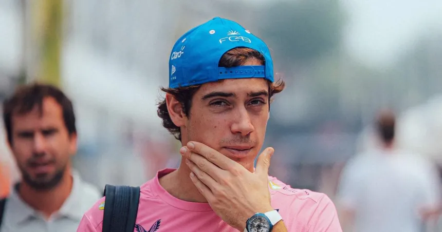Franco Colapinto con gorra azul y camiseta rosa en un entorno de automovilismo.
