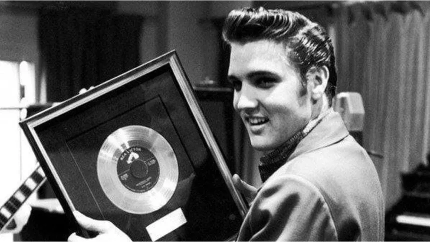 Elvis Presley sostiene un disco enmarcado.