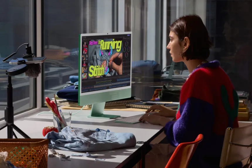 Una mujer trabaja frente a un iMac verde en un escritorio.
