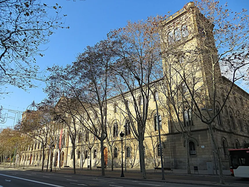 Fachada de un edificio de la Universitat de Barcelona junto a una avenida arbolada.