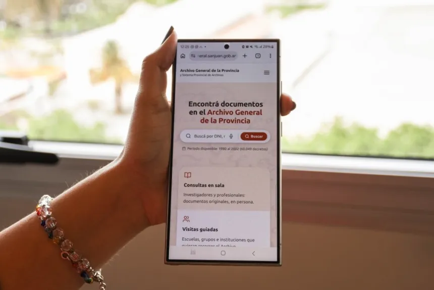 Una mano sostiene un celular con la página web del Archivo General de la Provincia.