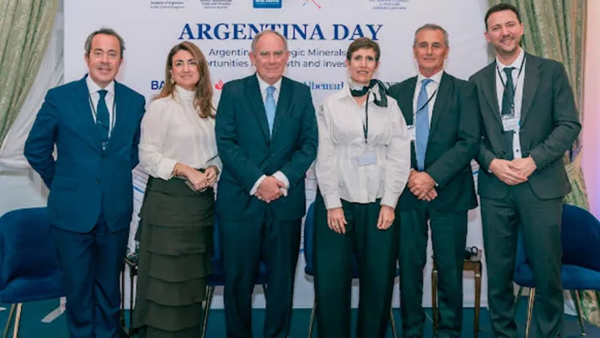 Seis adultos posan frente al cartel del foro Argentina Day.