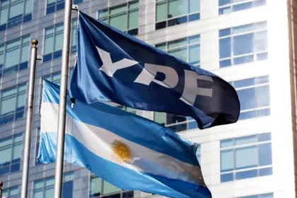 Bandera de YPF y bandera argentina frente a un edificio de oficinas.