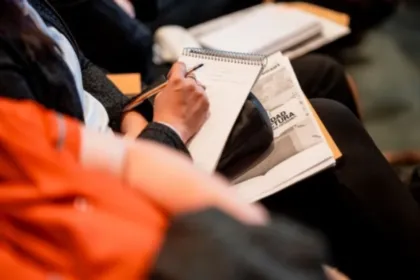 Una persona escribe en un cuaderno durante una reunión.