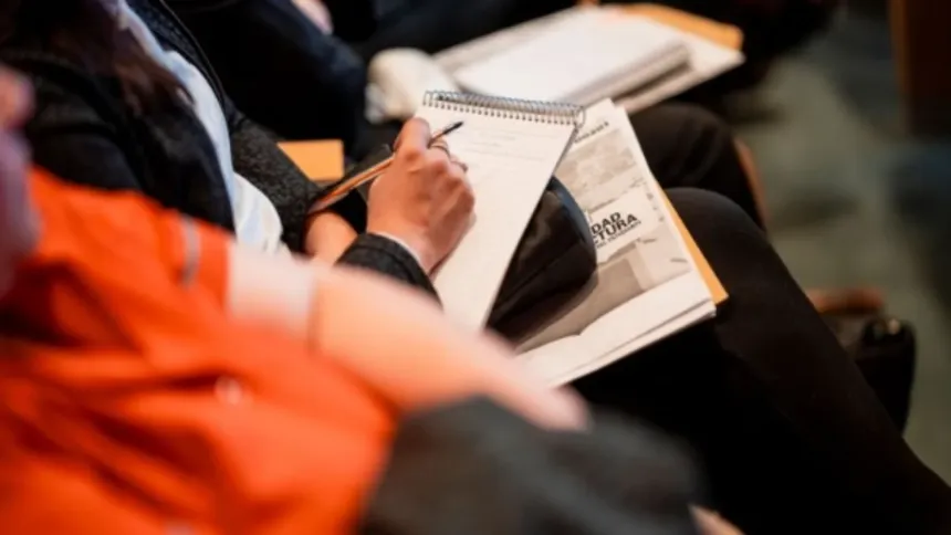 Una persona escribe en un cuaderno durante una reunión.