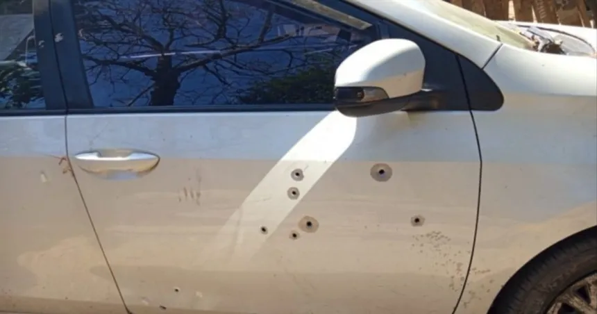 Puerta de un auto blanco con varios orificios de bala.