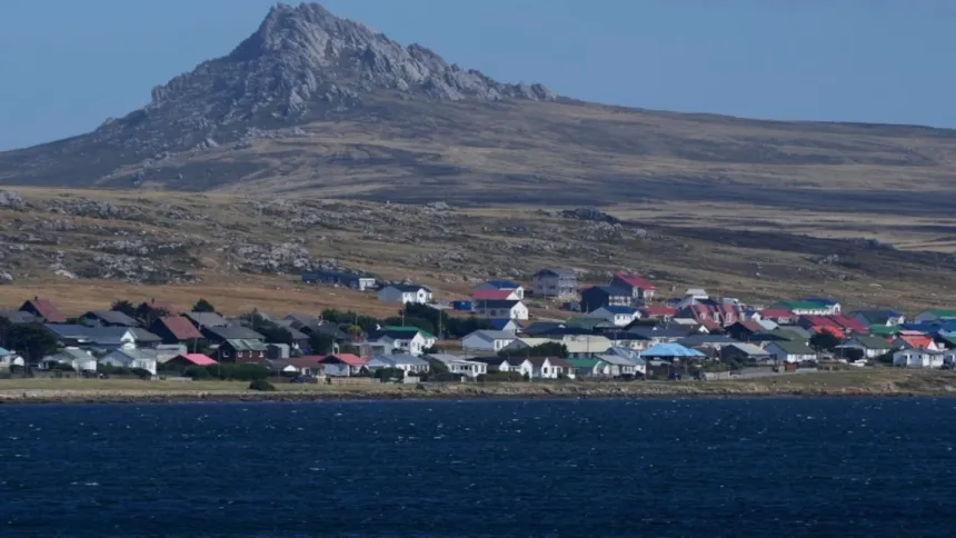 Un poblado costero de las islas Malvinas, con casas junto al mar y una montaña al fondo.