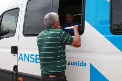 Un hombre entrega un papel por la ventanilla de una unidad móvil de ANSES.