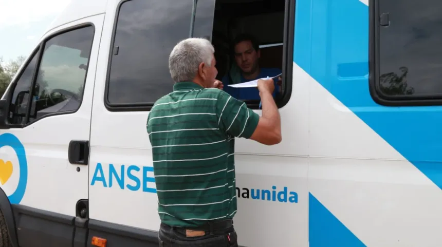 Un hombre entrega un papel por la ventanilla de una unidad móvil de ANSES.