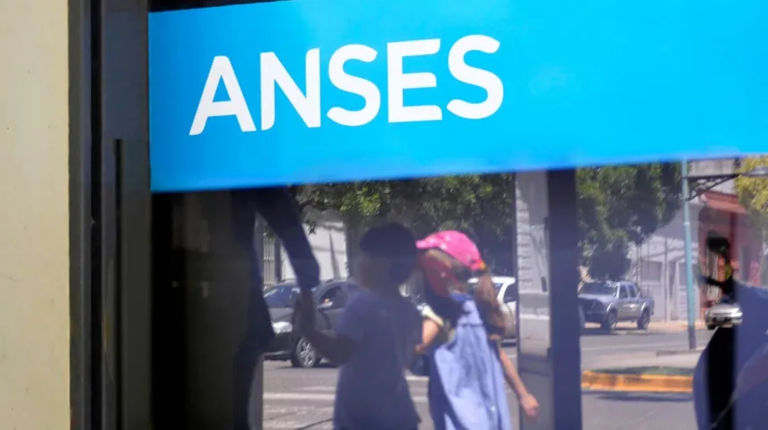 Cartel de ANSES en una vidriera con personas reflejadas.