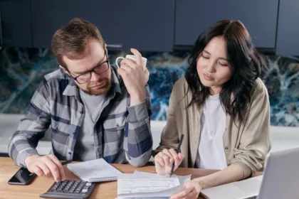 Una pareja revisa facturas y hace cuentas con una calculadora en su casa
