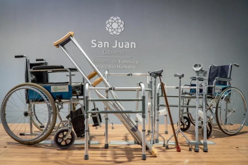 Sillas de ruedas, andadores y muletas exhibidos frente al logo del Gobierno de San Juan.