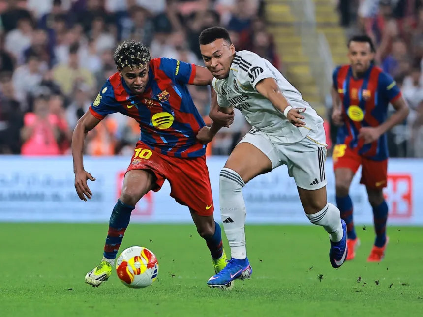 Un jugador del Barcelona y uno del Real Madrid disputan la pelota en la cancha.