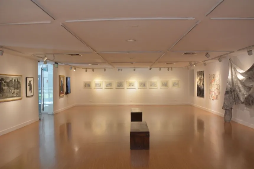 Una sala de museo exhibe dibujos enmarcados y otras obras de arte.