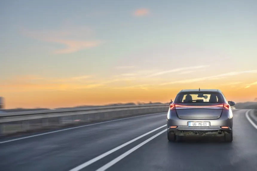 Un automóvil avanza por una autopista al atardecer.