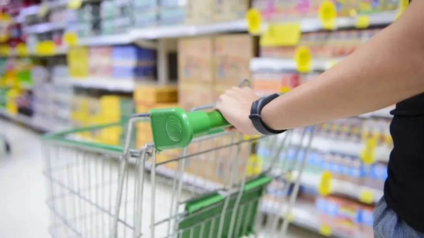 Una persona empuja un carrito entre las góndolas de un supermercado.