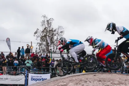 Varios ciclistas de BMX saltan en la pista ante el público.