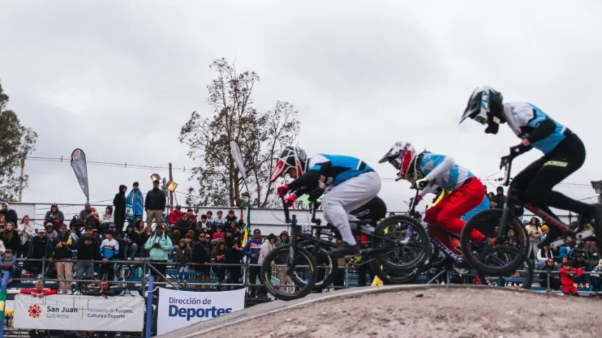 Varios ciclistas de BMX saltan en la pista ante el público.