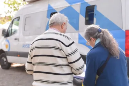 Dos adultos mayores junto a una unidad móvil de ANSES.