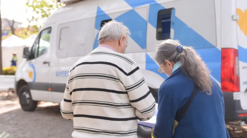 Dos adultos mayores junto a una unidad móvil de ANSES.