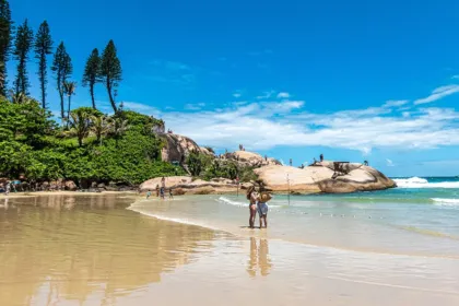 Playa de arena y mar en Brasil, con bañistas y rocas.