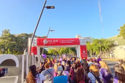 Personas con ropa violeta participan de una caminata bajo un arco del Gobierno de San Juan.