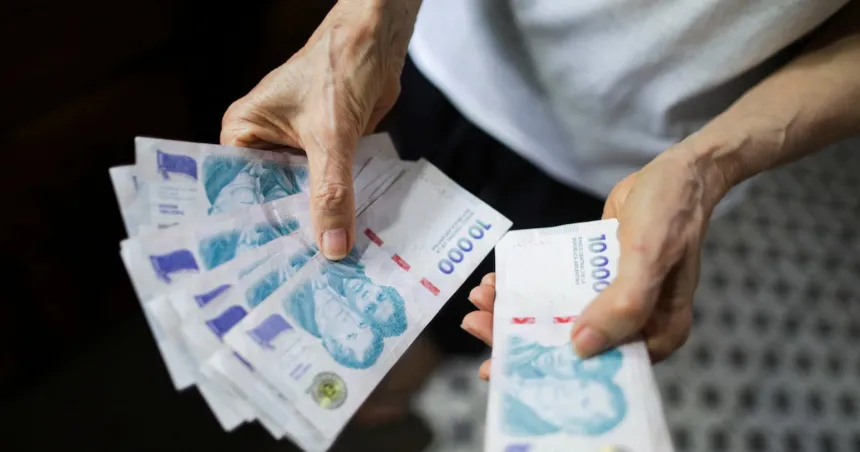 Manos contando billetes de 1.000 pesos argentinos.