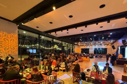 Asistentes comparten una gala en un salón con mesas y escenario.