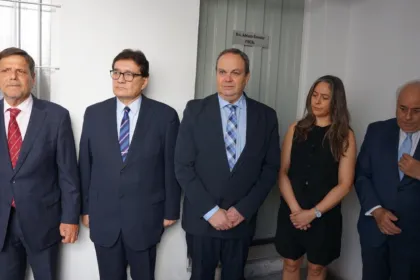 Cinco adultos posan en un pasillo institucional, junto a la puerta de un consultorio.