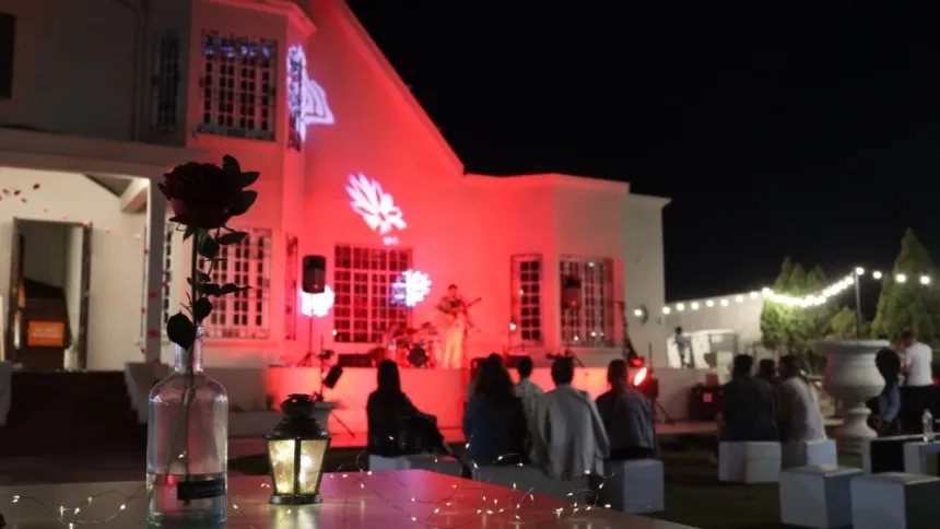 Público escucha un recital nocturno frente al Chalet Cantoni, iluminado de rojo.