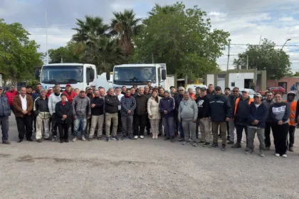 Empleados municipales posan frente a dos camiones.