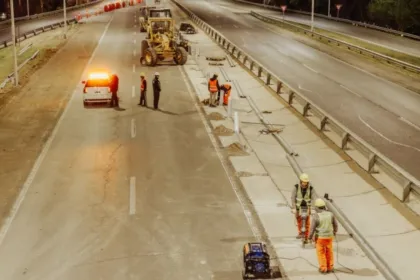 Obreros y maquinaria trabajan en la repavimentación de una avenida.