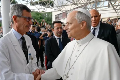 El papa León XIV saluda a un médico con bata blanca.