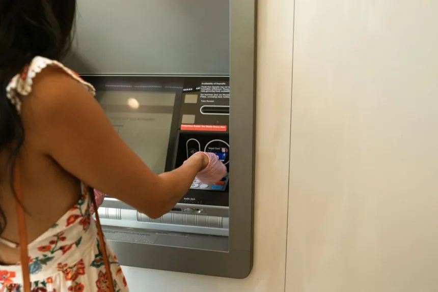Una mujer opera un cajero automático para retirar dinero.