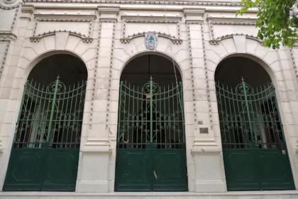 Fachada de un edificio público sanjuanino con arcos, portones verdes y escudo provincial.