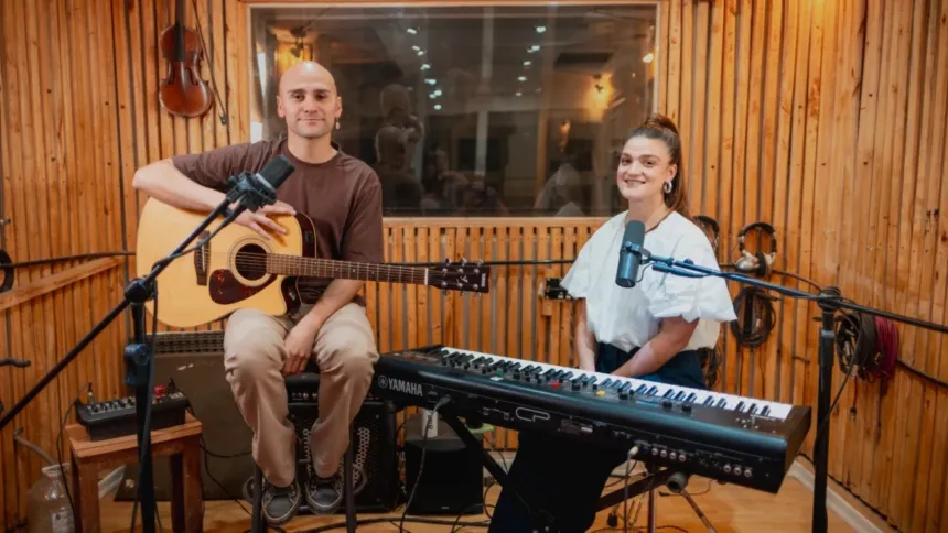 Dos músicos con guitarra y teclado en un estudio de grabación.