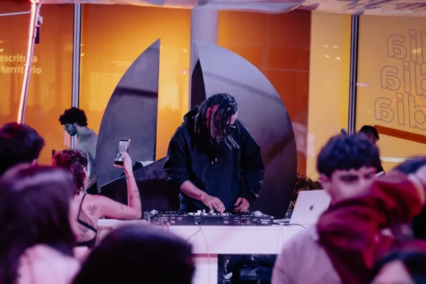 Un DJ toca frente a un público en un espacio cultural.