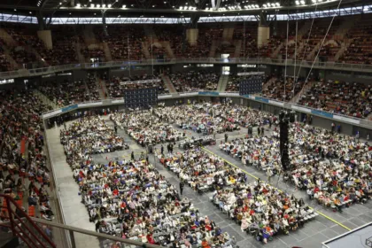 Miles de personas sentadas en un estadio techado durante una convención de los testigos de Jehová.