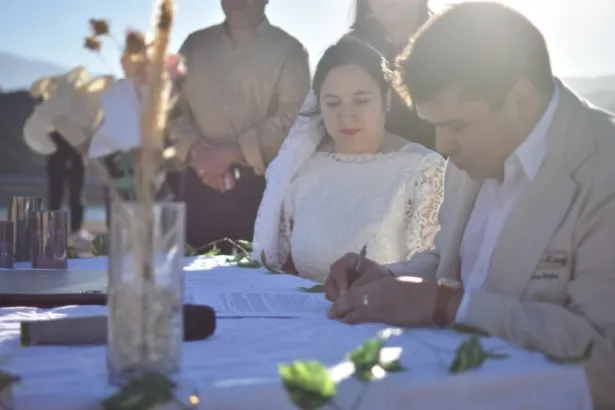 Una pareja firma el acta durante una ceremonia de casamiento al aire libre