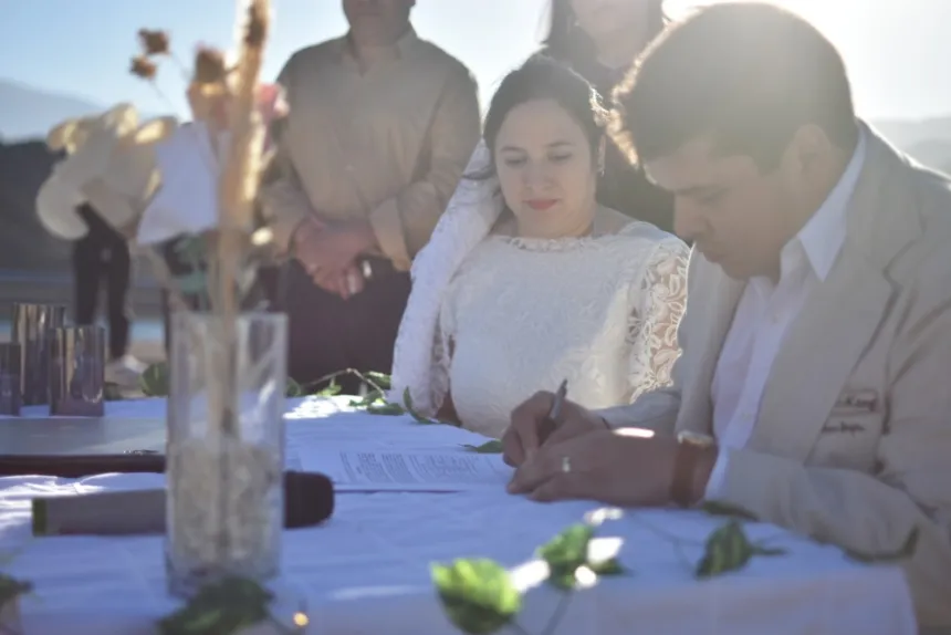 Una pareja firma el acta durante una ceremonia de casamiento al aire libre