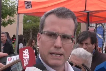 Un hombre brinda declaraciones bajo una carpa identificada con el logo de la COPRE.