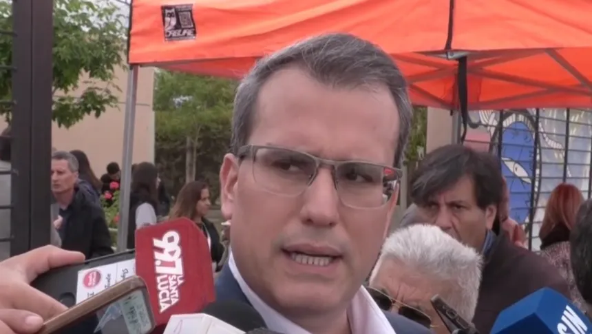Un hombre brinda declaraciones bajo una carpa identificada con el logo de la COPRE.