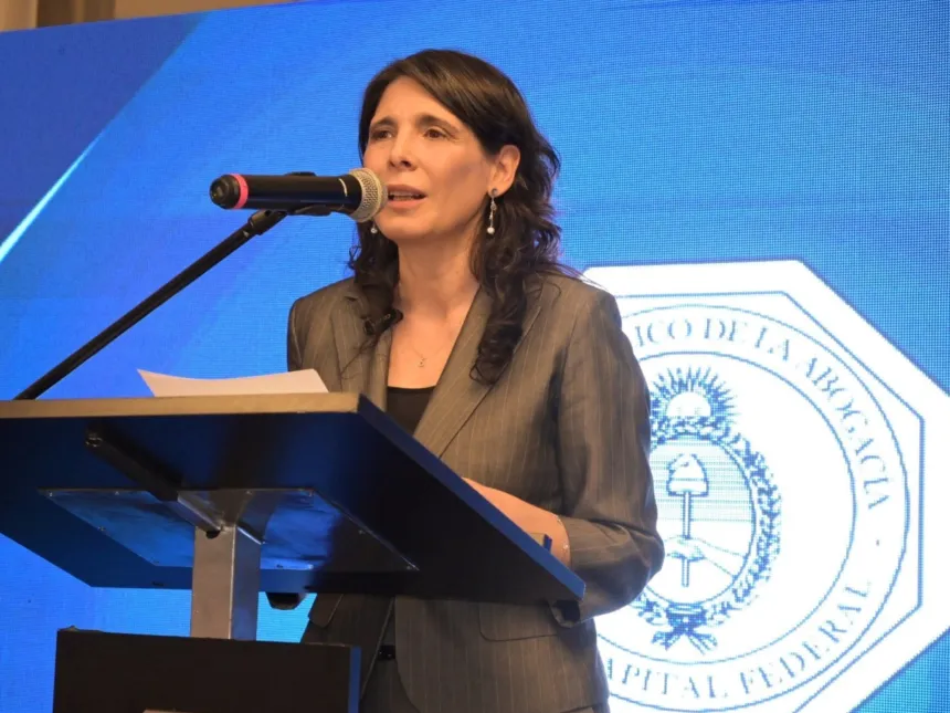 Una mujer adulta habla desde un atril ante el emblema de un colegio de abogados.